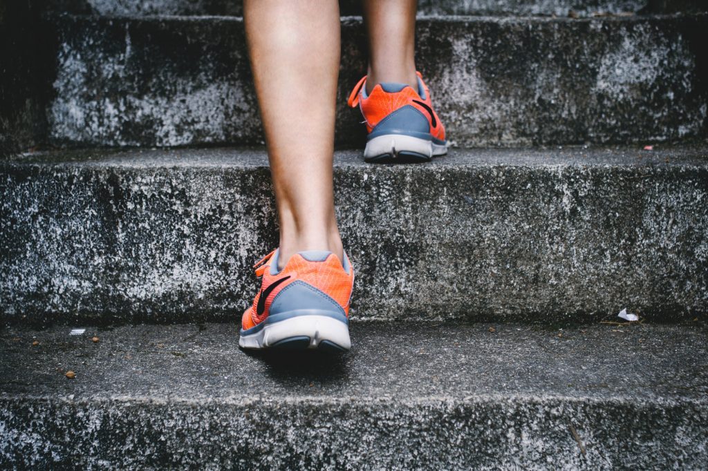 An image of a person running up the stairs. Only showing ankles and feet.