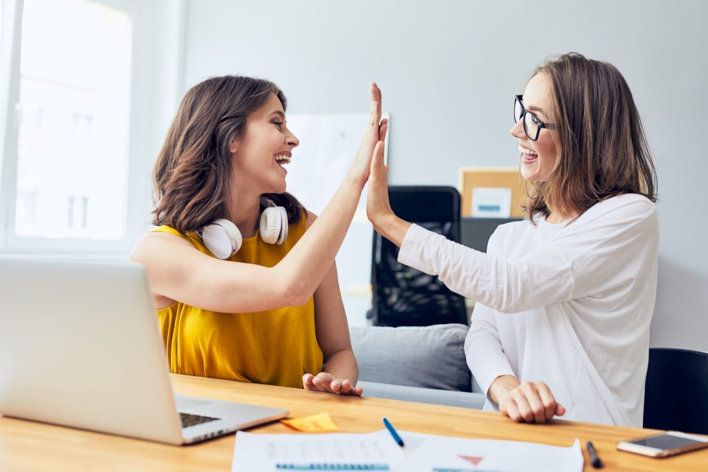 Two happy women high-fiving in an office
