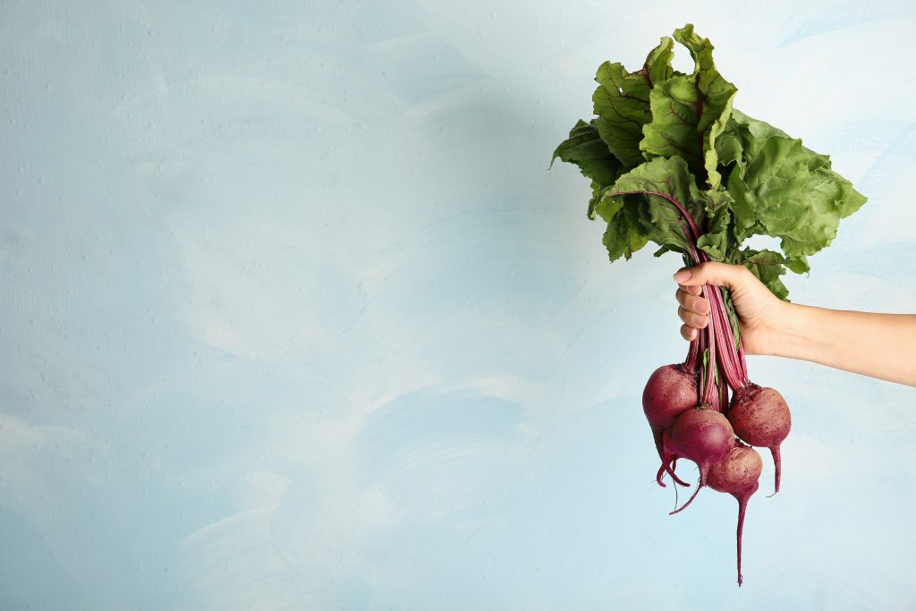 A hand holding a bunch of beets