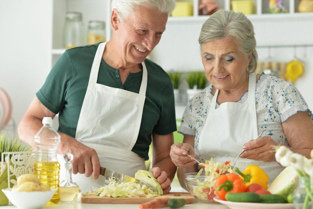 A senior couple cooking together preparing a healthy meal