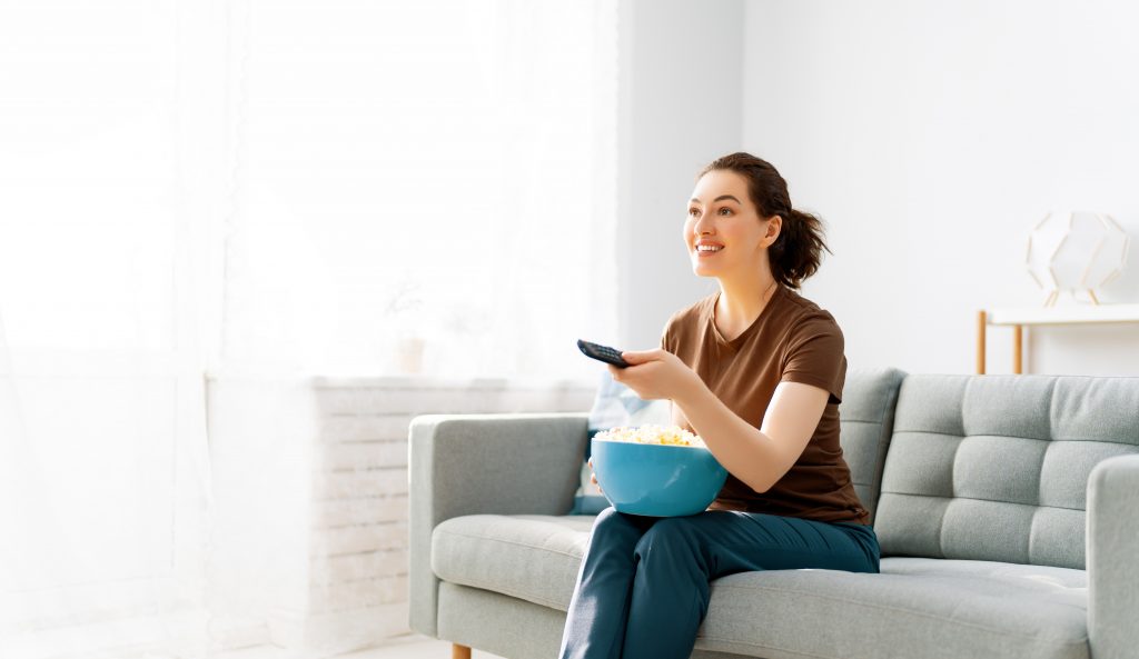 Young woman watching TV and eating popcorn